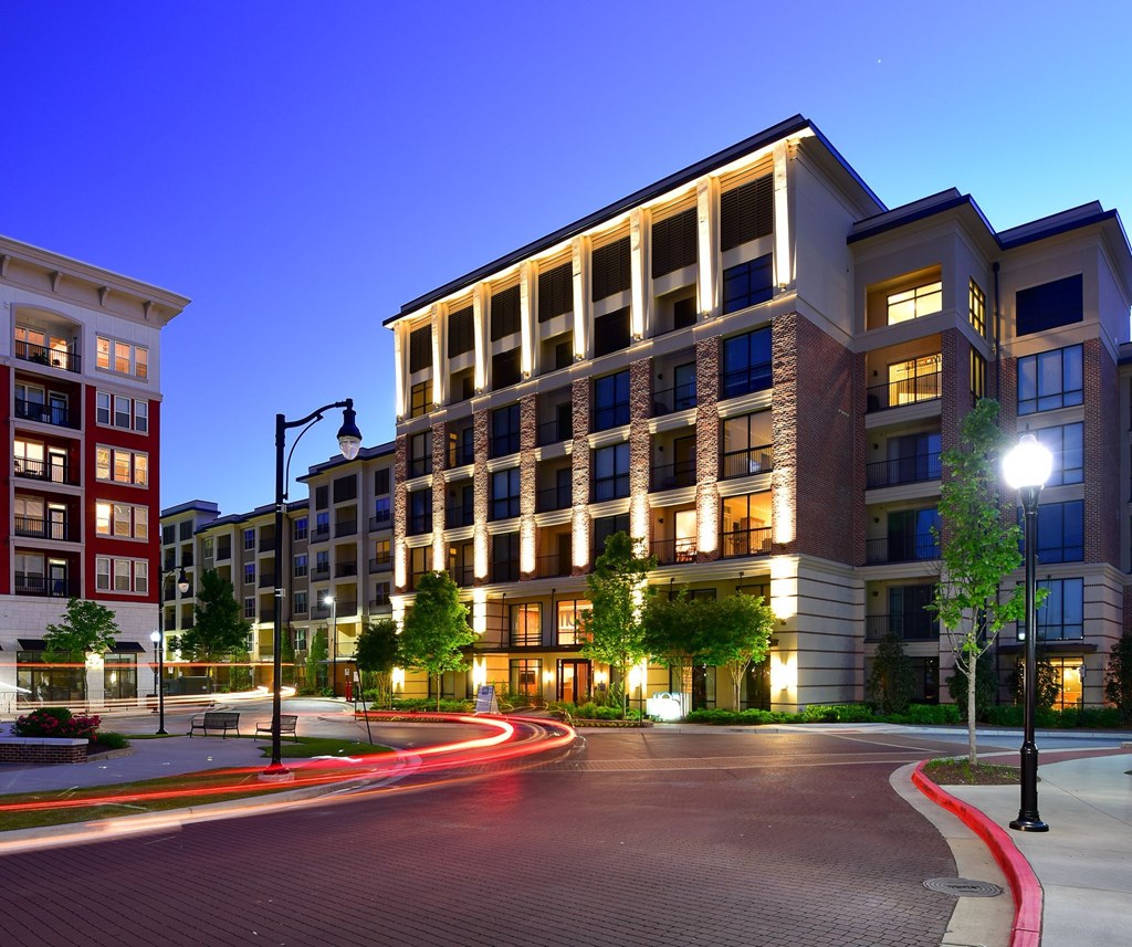 A modern apartment building with a lit walkway in front.