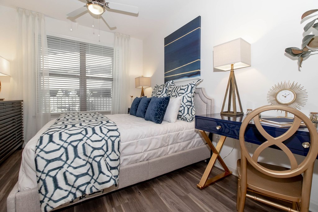 A bedroom with a bed, chair, and a ceiling fan.