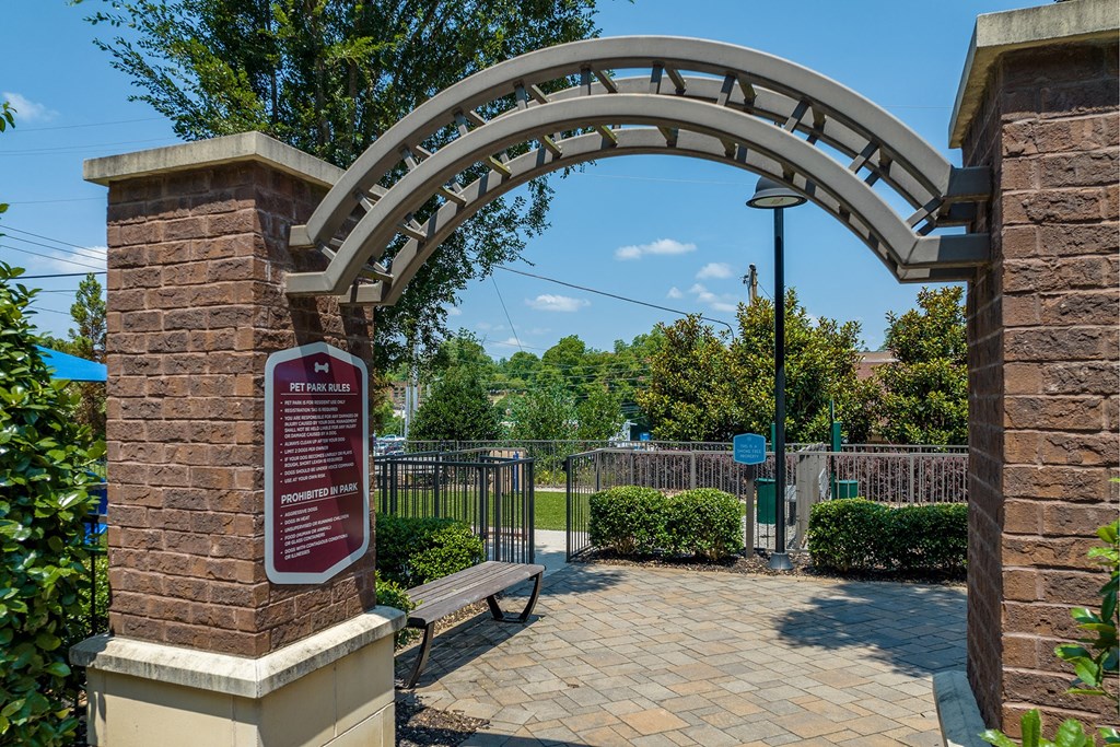 a stone archway with a bench in front of a park