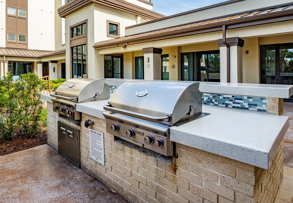 a large stainless steel grill sits on a stone counter outside of a building