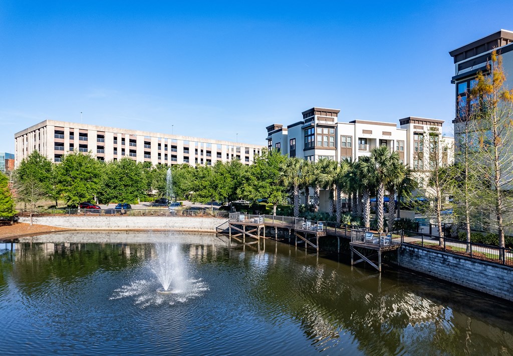 a fountain in a pond with buildings in the background