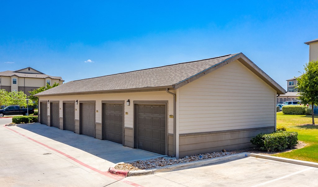 a small building with three garage doors on the side of a driveway