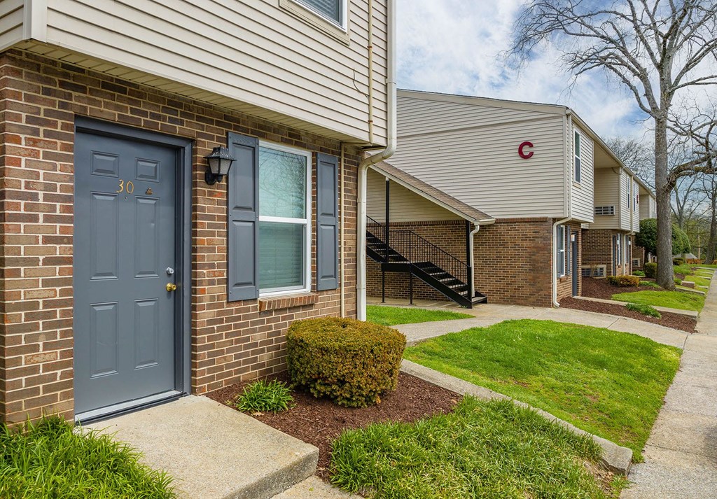 a blue door on a brick building with green grass and a tree in the background