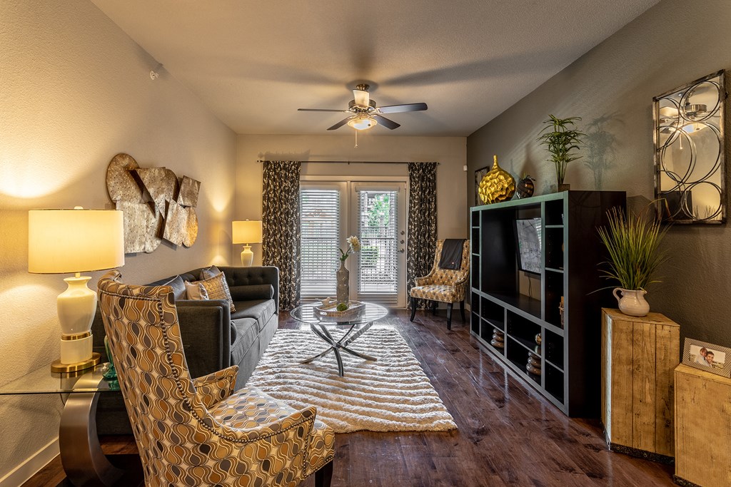 a living room with a ceiling fan and a door to a balcony
