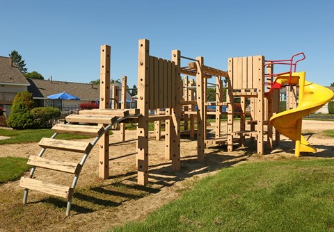 a playground with a yellow slide and wooden steps