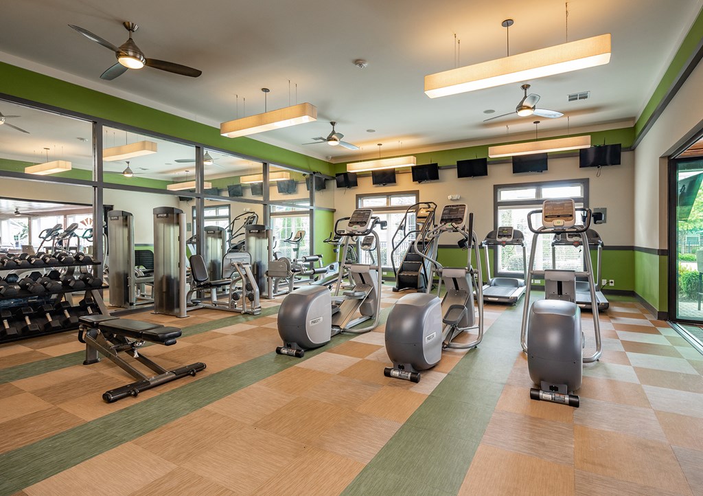 a gym with treadmills and other exercise equipment in a building with green walls