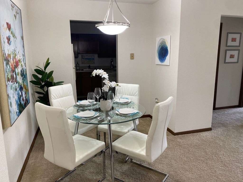a dining room with a glass table and white chairs at Winchell Way Apartment , Kalamazoo, MI
