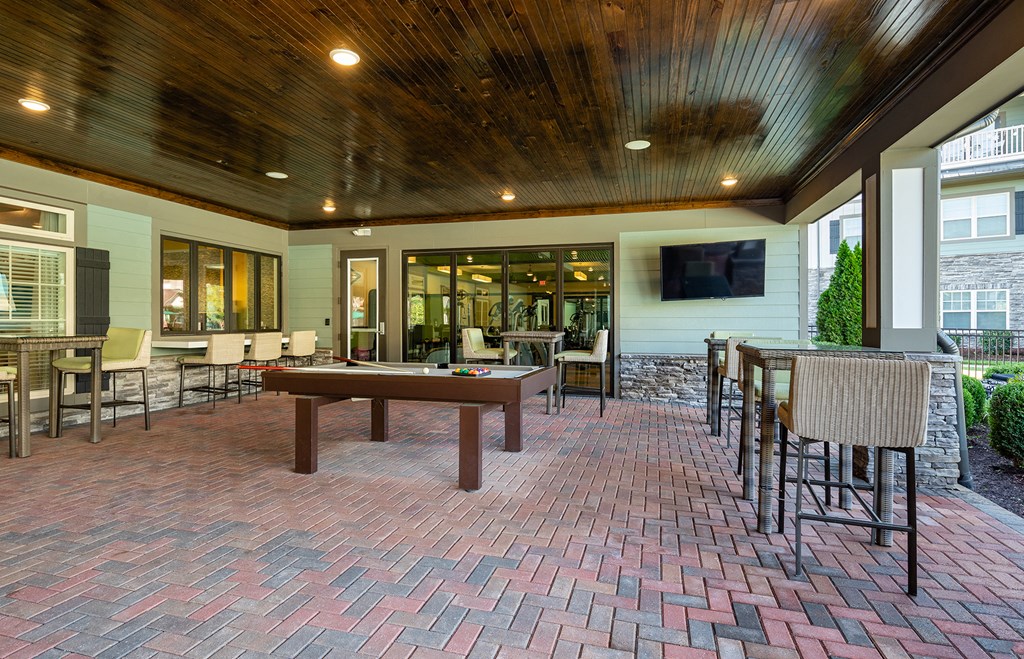 a covered patio with a pool table and tables