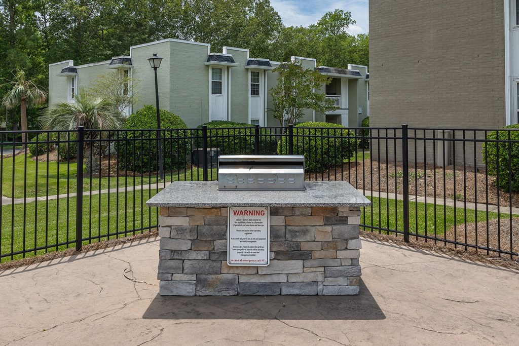 a sign in front of a fence with apartments in the background