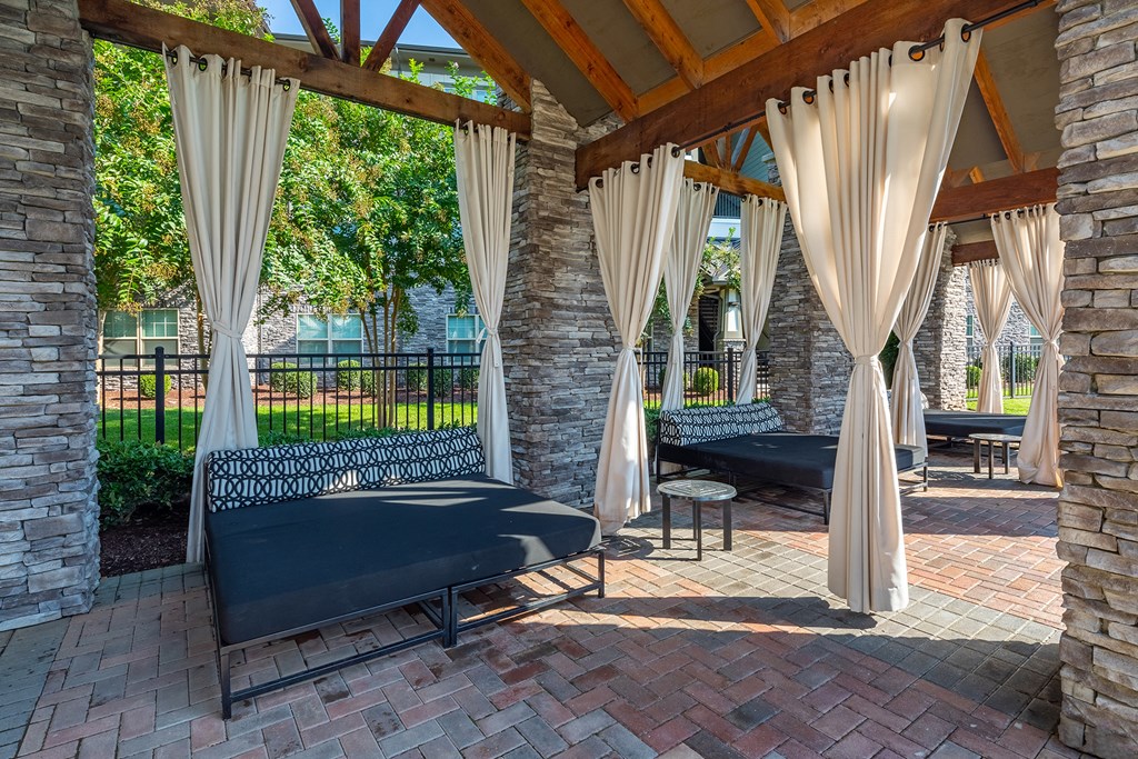 a covered patio with couches and curtains