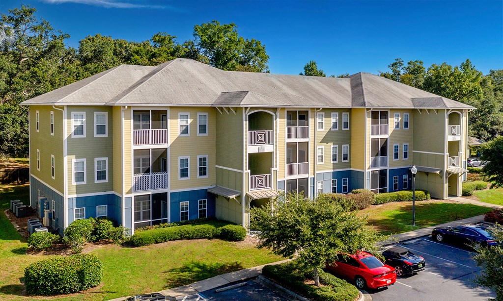 an aerial view of an apartment building with cars parked outside