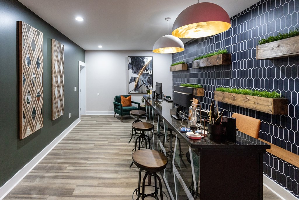 a room with a desk and stools in front of a wall with a geometric pattern