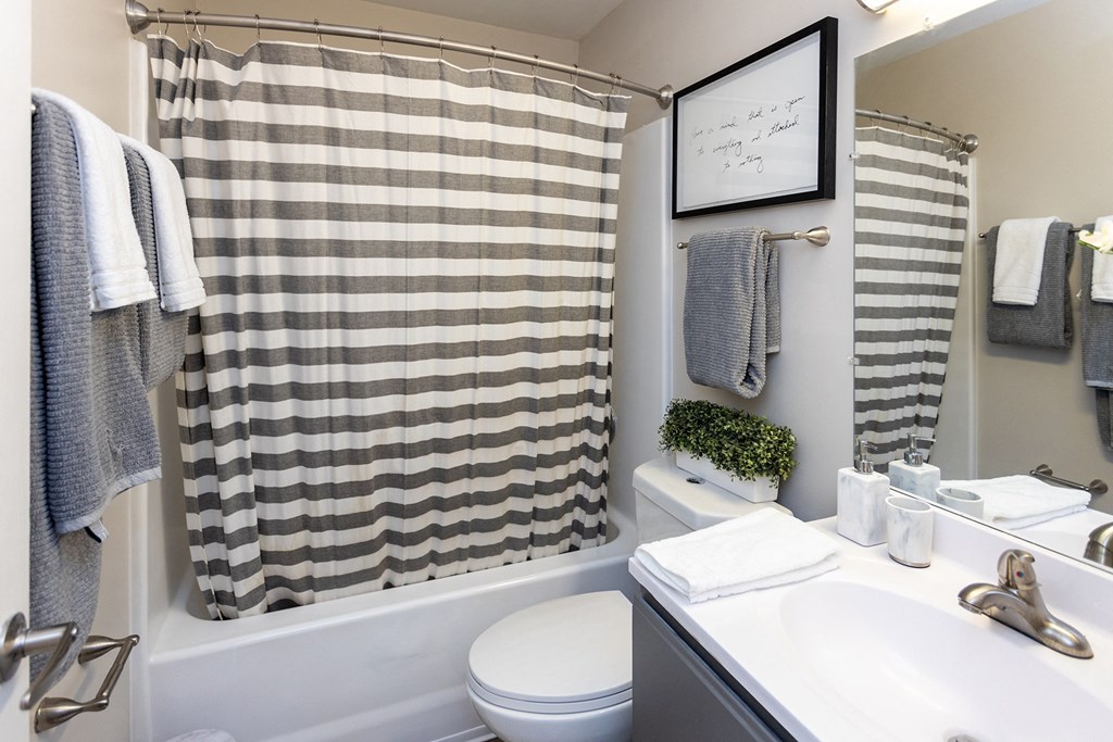 a bathroom with a white sink and toilet next to a bathtub with a shower curtain and