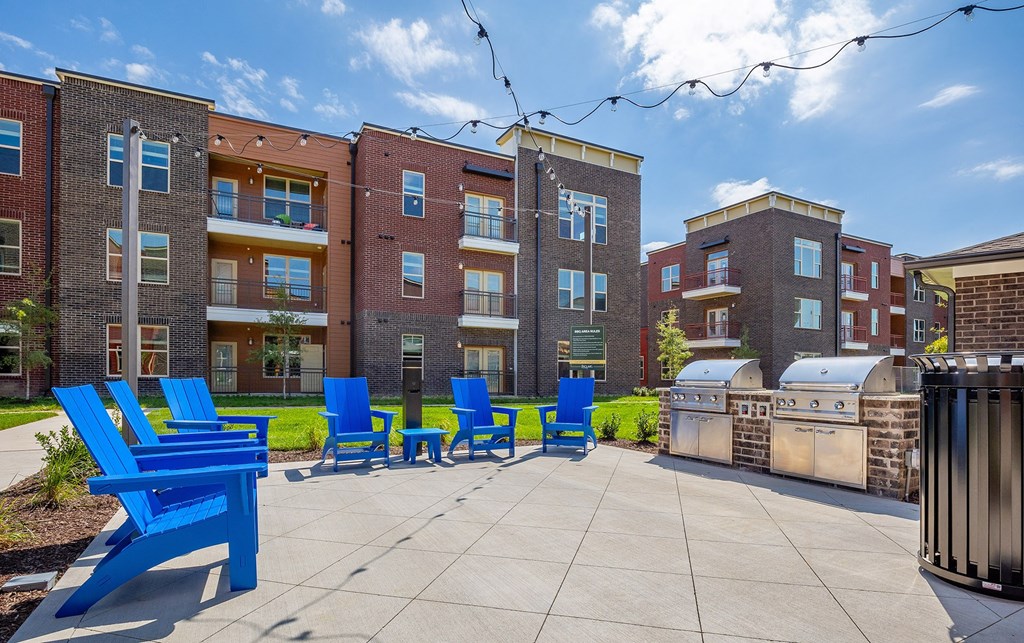 our apartments have a large patio with blue chairs and a grill