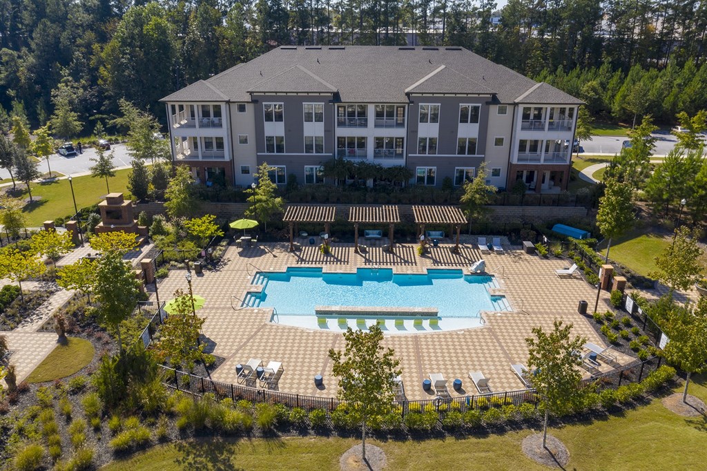 an aerial view of an outdoor pool with a building in the background