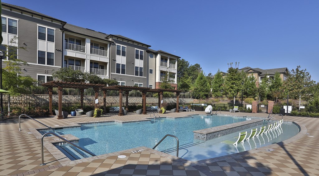 a swimming pool with chairs in front of an apartment building