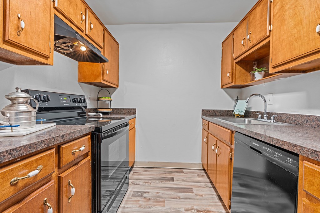 a kitchen with wood cabinets and black appliances and a sink