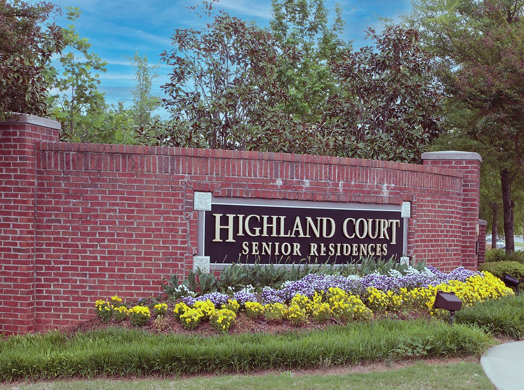 a brick retaining wall with a sign for highland court senior residences