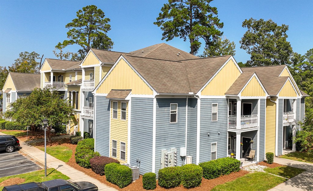 an apartment building with blue and yellow siding and a parking lot