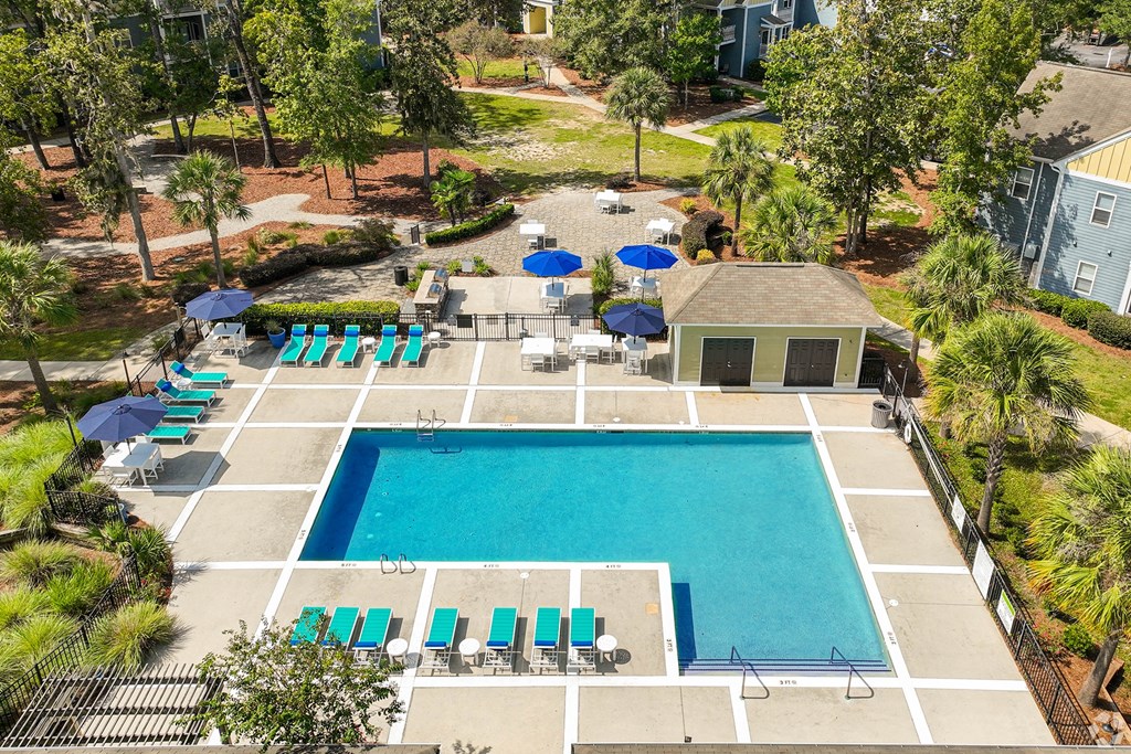 a swimming pool with chairs and umbrellas in front of a house
