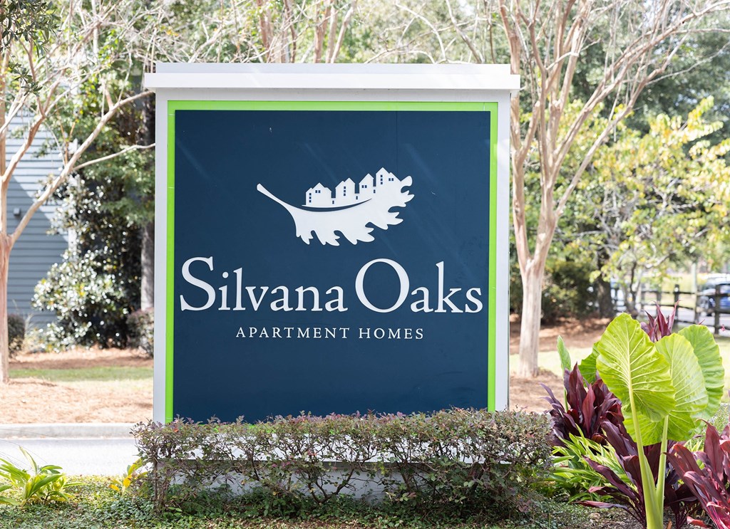 a sign apartment homes in front of a garden