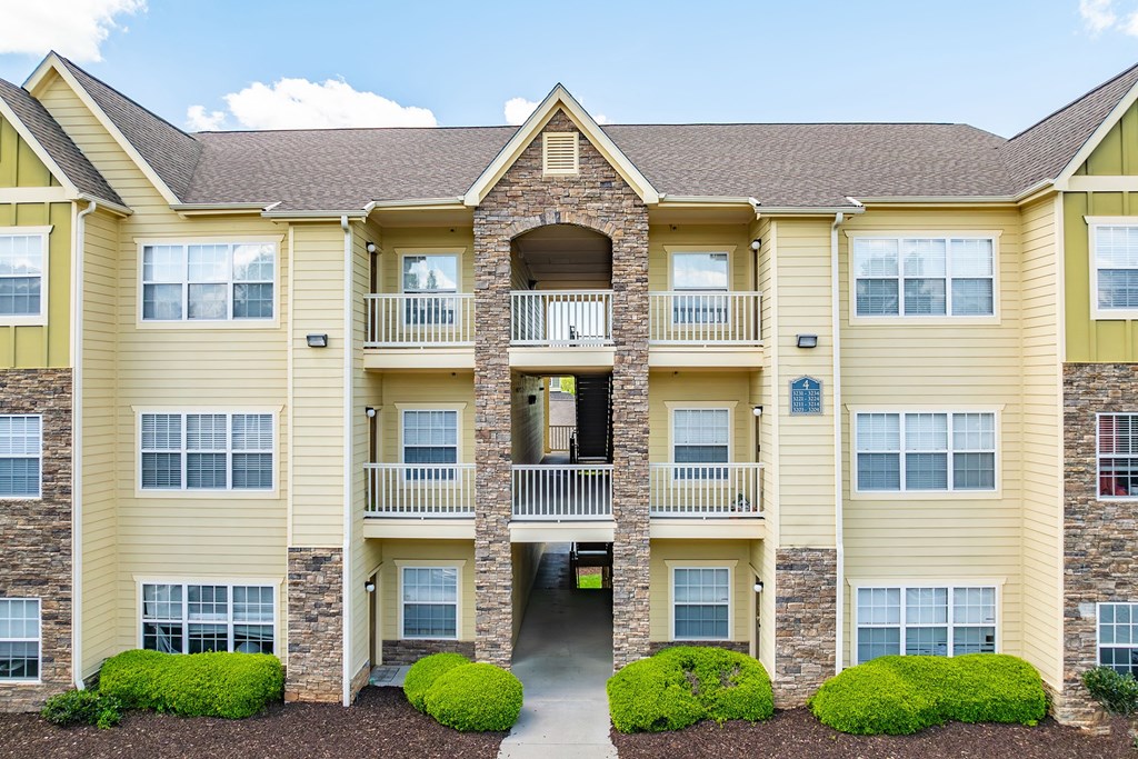 the exterior of an apartment building with shrubs