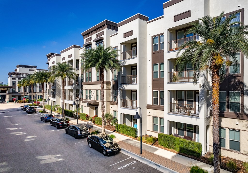 an apartment building with palm trees and cars parked in front of it