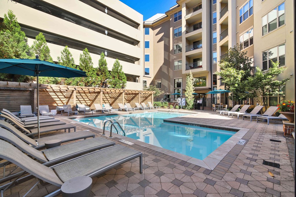 A large swimming pool surrounded by sun loungers and umbrellas.