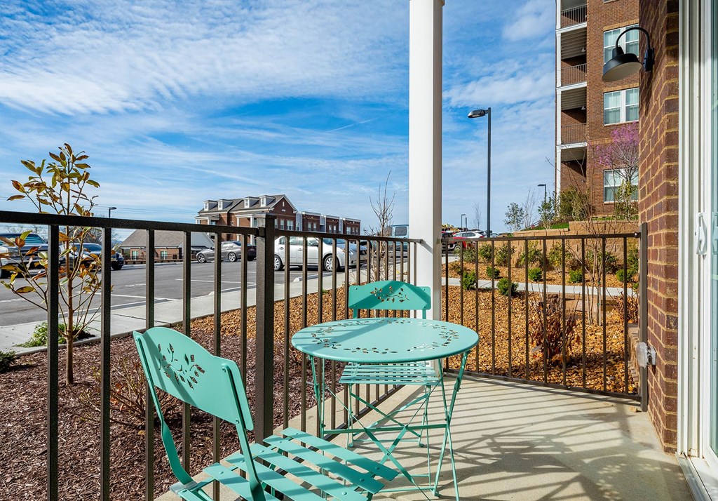 the private balcony has a table and two chairs and overlooks the parking lot