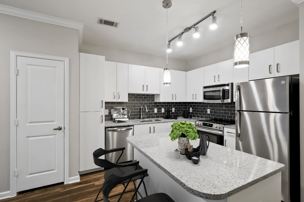 A kitchen with a white counter top and a stainless steel refrigerator.