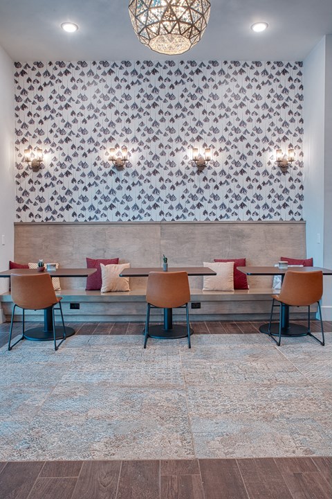 A dining room with a patterned wallpaper and a bench with chairs.