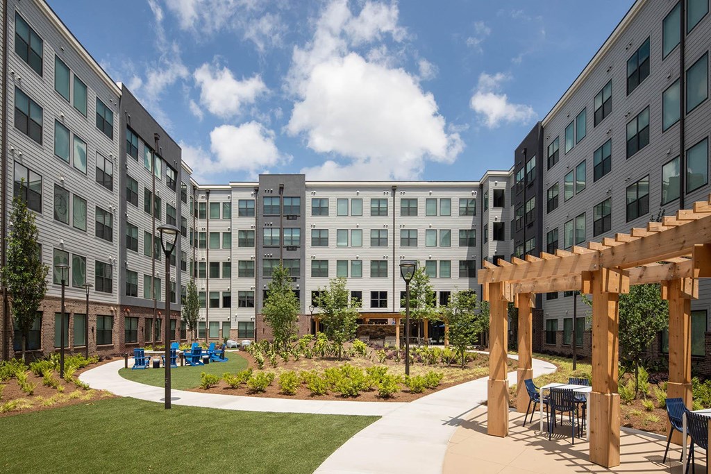 a courtyard with tables and chairs in front of an apartment building