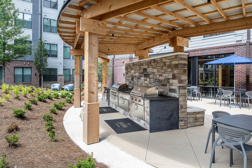 a covered patio with a grill and tables and chairs
