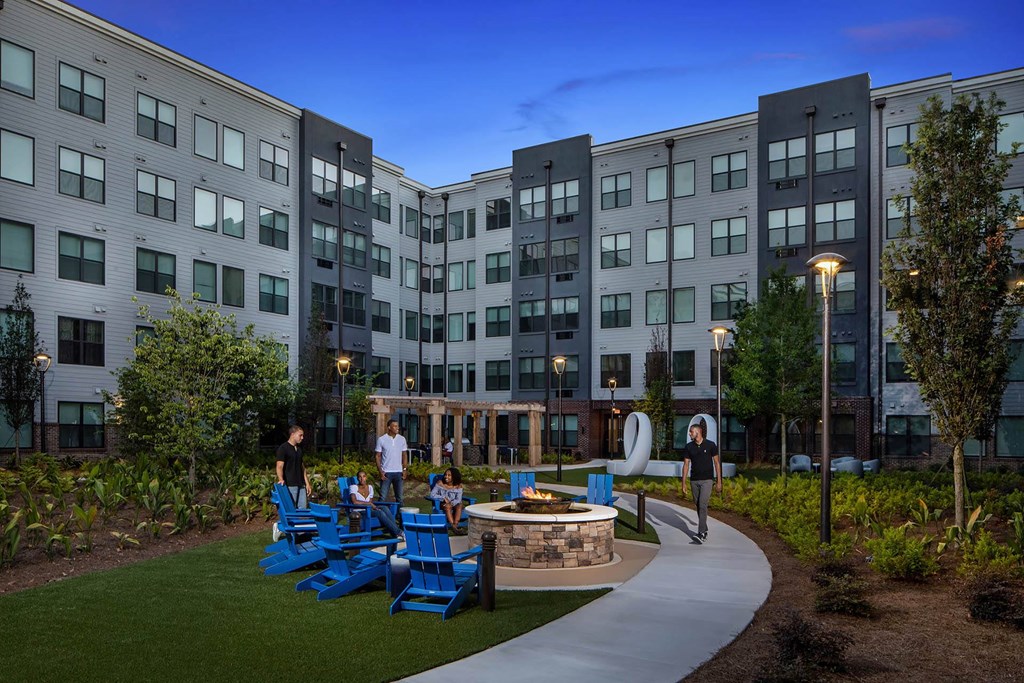 a courtyard with blue chairs and a fire pit in front of an apartment building
