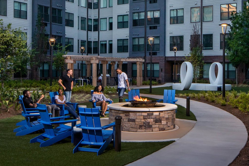 a group of people sitting around a fire pit in front of an apartment building