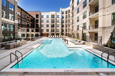 A large outdoor swimming pool surrounded by apartment buildings.