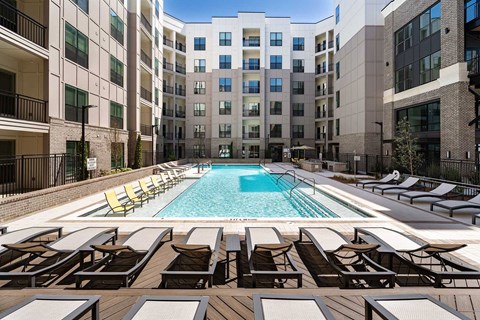 A pool surrounded by sun loungers and chairs.