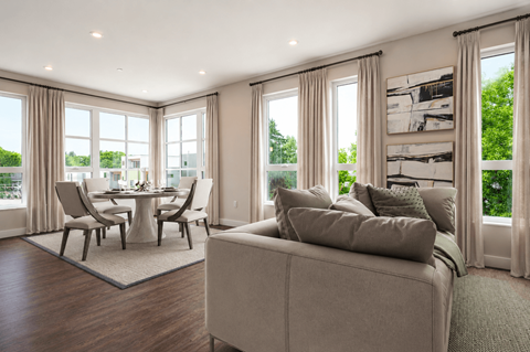 A modern living room with a grey sofa and a dining table with chairs.
