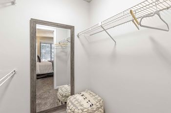 A white closet with a mirror and a shelf.