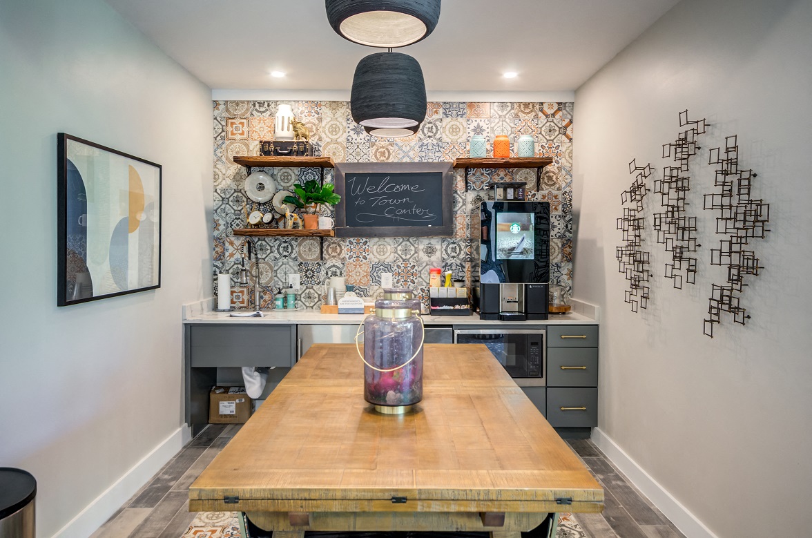A kitchen with a wooden table and a chalkboard sign on the wall.