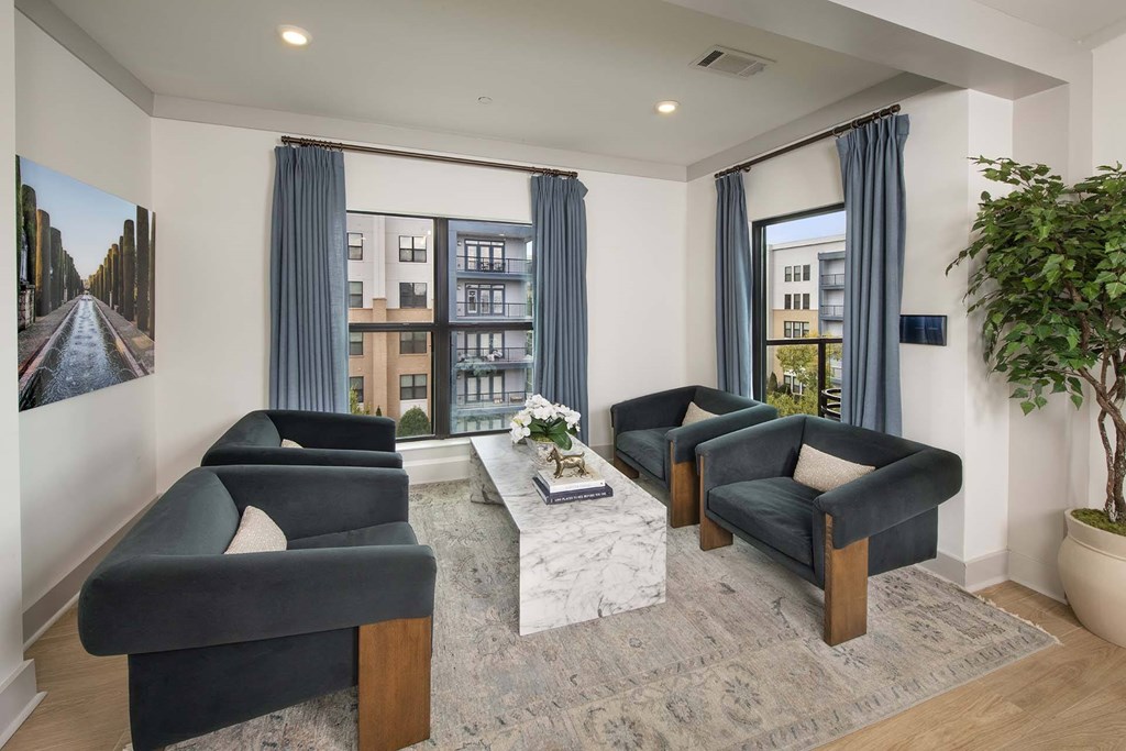 A living room with a large window, a sofa, a chair, a coffee table, and a potted plant.