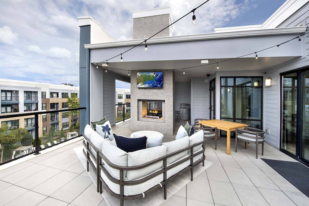 A modern outdoor patio with a white couch and a wooden table.