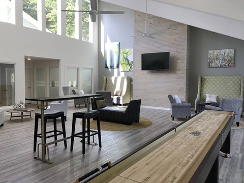 A modern living room with a long wooden table and bar stools.