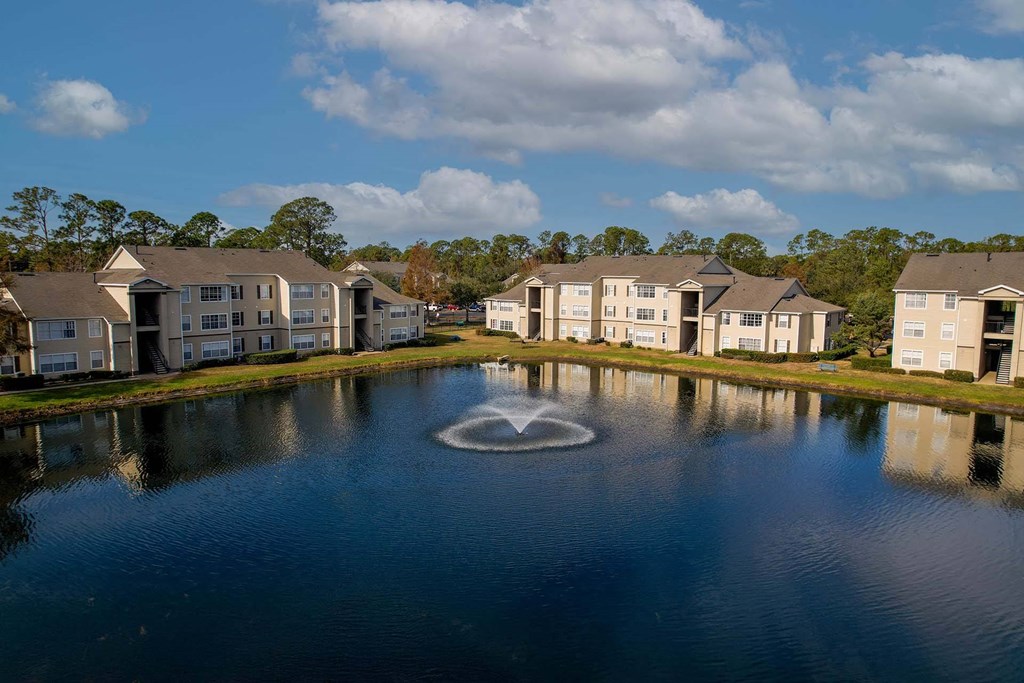 A fountain in the middle of a lake surrounded by houses.