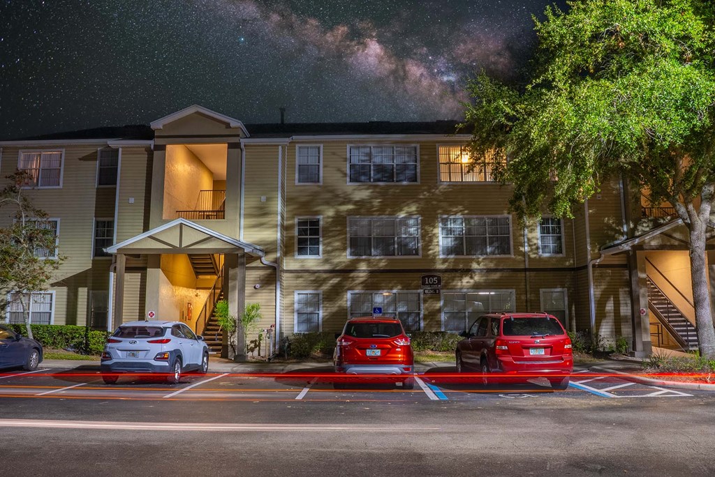 A building with a parking lot in front of it at night.