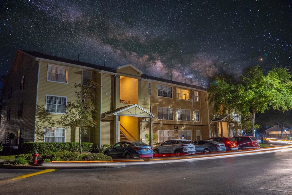 A building with a parking lot in front of it at night.