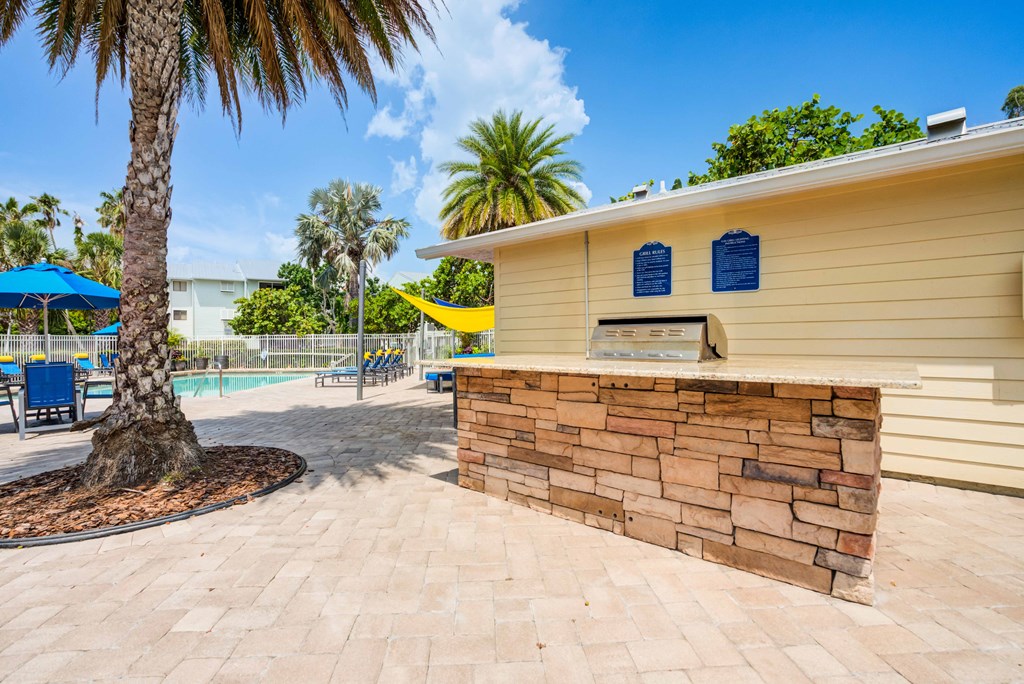 A yellow building with a stone wall and a palm tree in front.