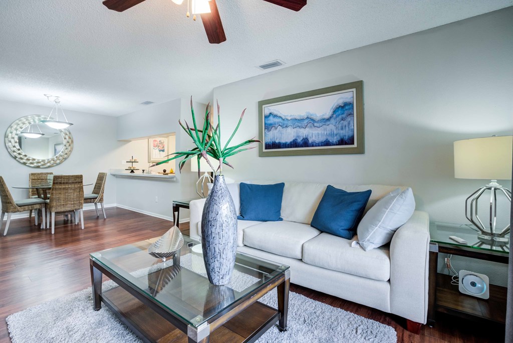A living room with a white couch and a glass coffee table.
