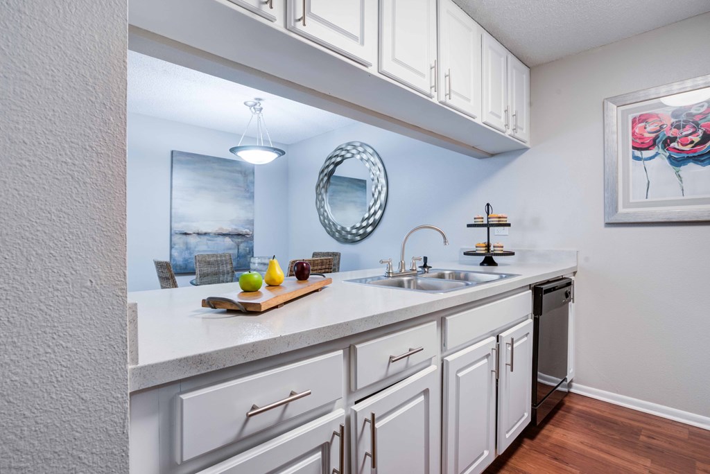A kitchen with white cabinets and a wooden cutting board on the counter.
