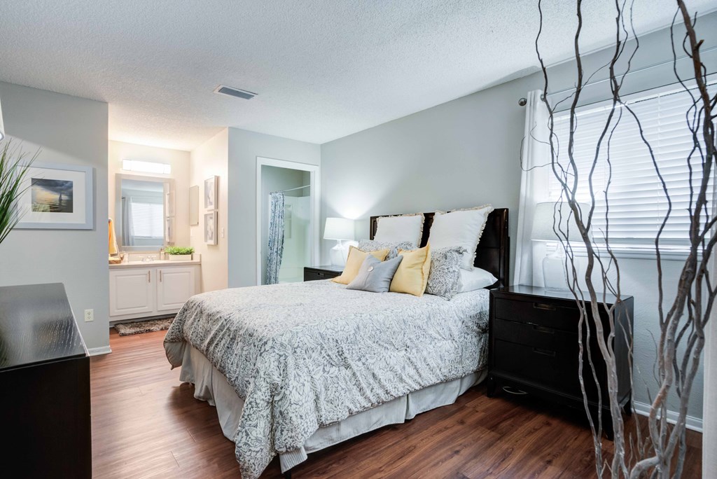 A bedroom with a large bed and a plant.